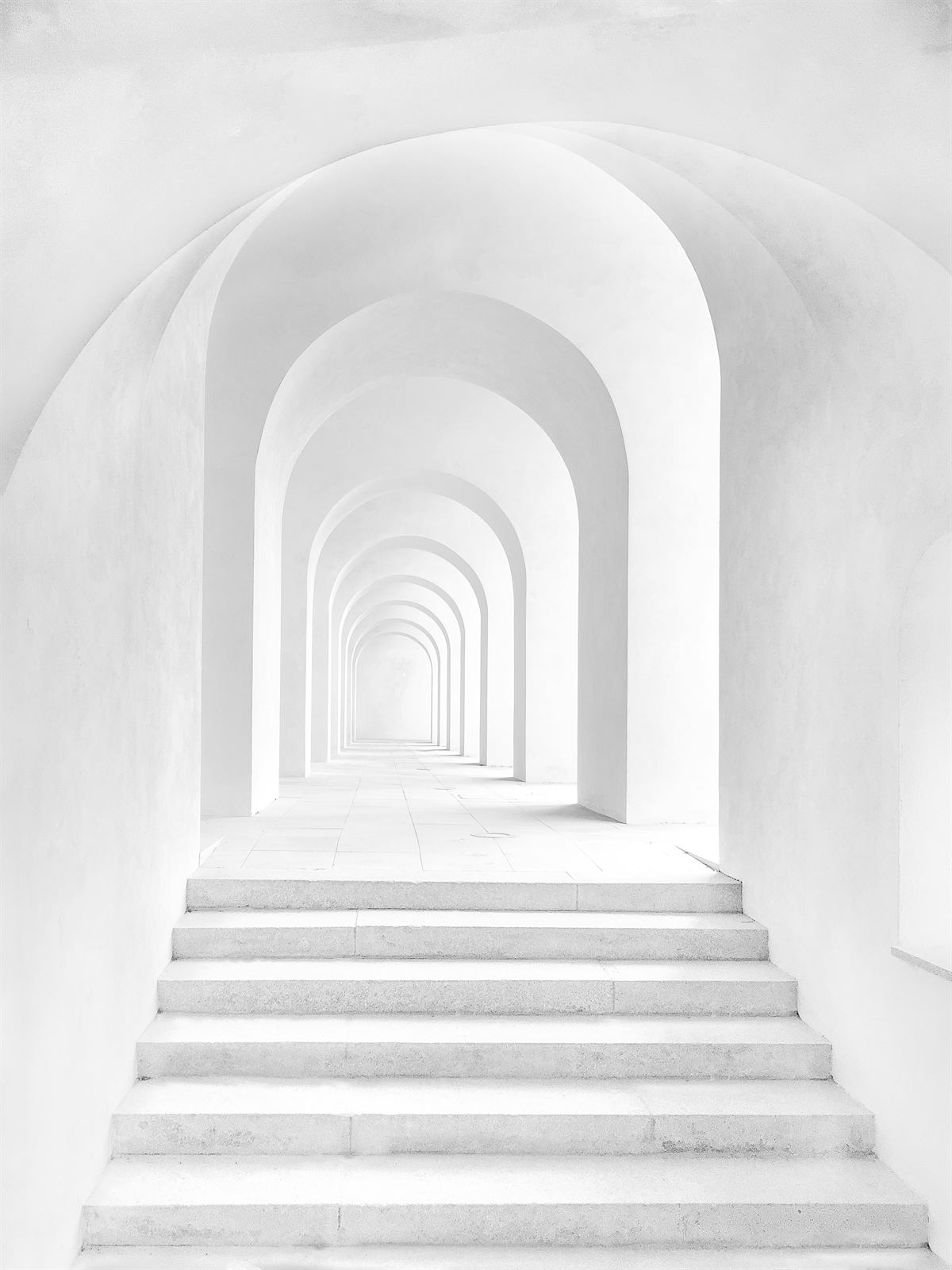 White arched corridor with steps leading forward